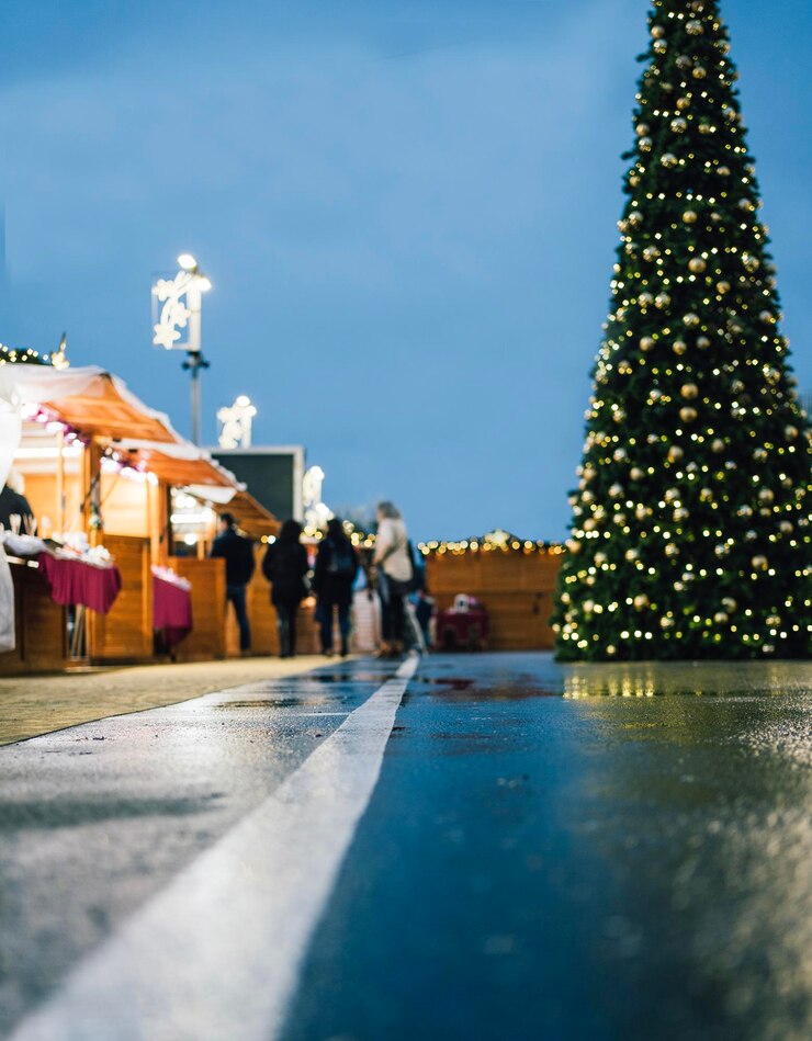Foto mercado de natal ocorrendo em um parque visão de ângulo baixo de alguns fornecedores presentes com uma grande árvore de natal e decoração