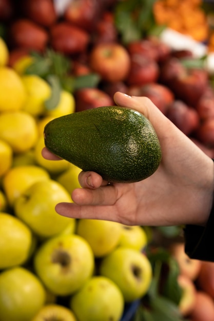 Mercearia com frutas e legumes vegetarianos frescos e saudáveis Uma garota está escolhendo abacate