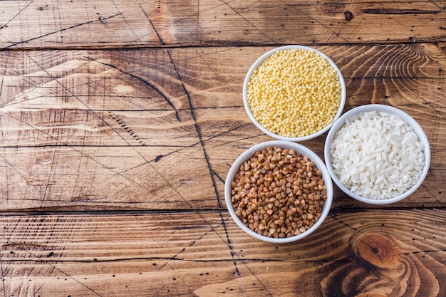 Mercearia de cereais secos. arroz, trigo sarraceno e milho na mesa de madeira.