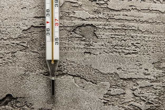Mercury klassisches Körperthermometer, auf einem Beton liegend, Grad Celsius.