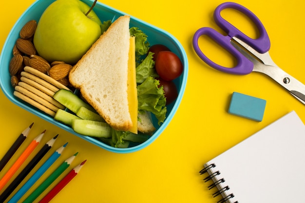 Foto merenda escolar na caixa, lápis e caderno