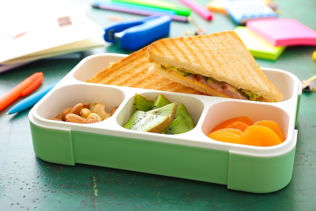 Merendeira escolar com comida saborosa e papelaria na mesa