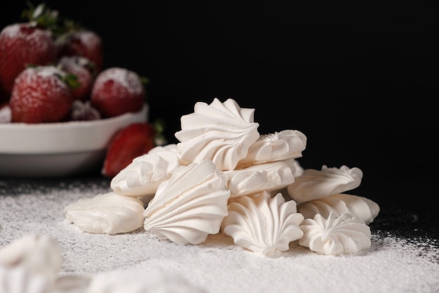 Merengue de cerca y fresas en un plato sobre un fondo negro