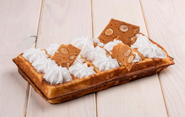 Merengue de waffle belga e chips de amêndoa Sobre um fundo claro de madeira