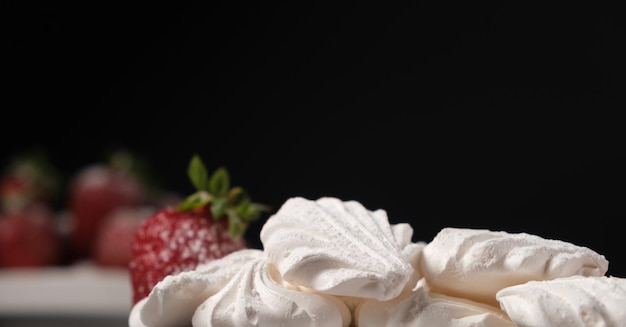 Merengue y fresas sobre un fondo negro