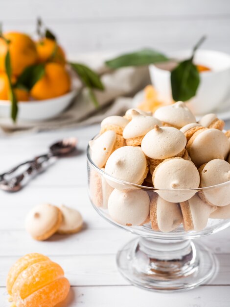 Merengue de galletas en un vaso de mandarinas con hojas verdes en un plato sobre fondo blanco