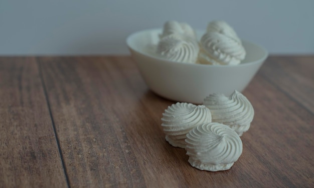 merengue en un plato blanco sobre un fondo blanco y una superficie de madera