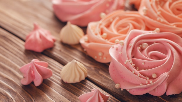 Merengue rosa pálido en forma de rosa o flor. el merengue es una gran cantidad de decoración de pasteles, primer plano.