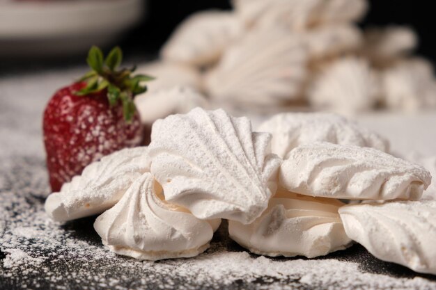 Merengues aireados y fresas sobre azúcar glas