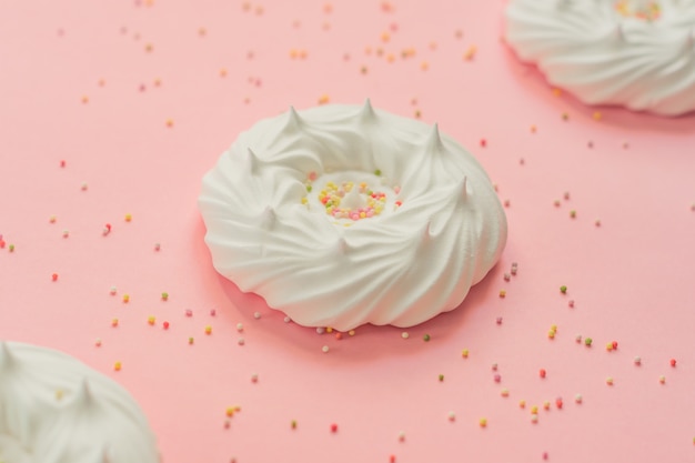 Foto merengues caseros de aire blanco y decoraciones de confitería en rosa