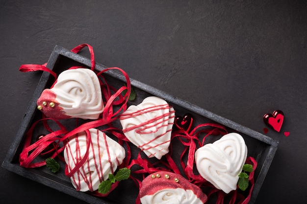 Merengues caseros en forma de corazón en caja de madera antigua para el día de San Valentín, vista superior, espacio de copia