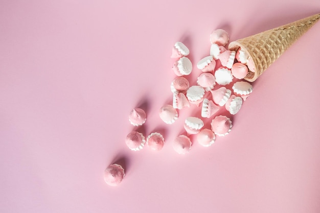 Merengues coloridos y brillantes en galletas de gofres se encuentran sobre un fondo rosa