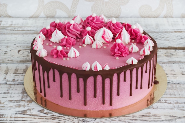 Merengues de bolo de creme-de-rosa com manchas de chocolate em um fundo branco de madeira