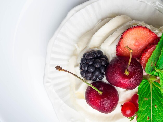 Merengues pastel de pavlova con cereza fresca mora fresa sobre fondo de hormigón