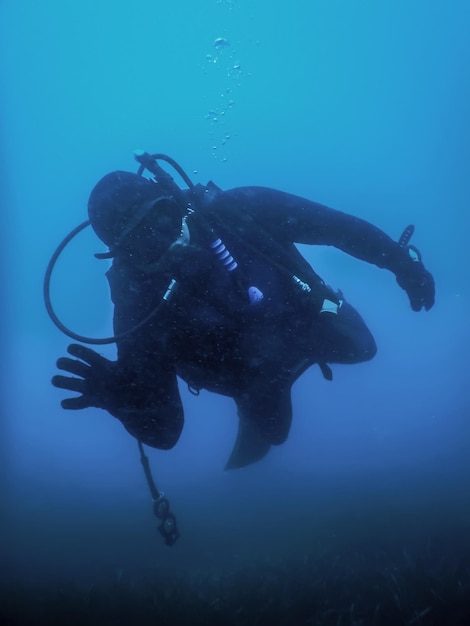 Mergulhador nadando em uma água azul, olhando para a câmera
