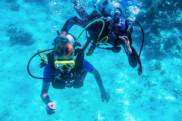 Mergulhadores treinando embaixo d'água perto de recifes de coral