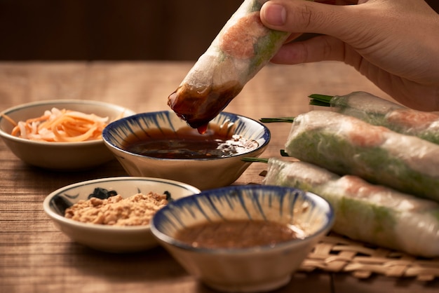 Foto mergulhando rolos de papel de arroz vegetariano à mão no molho de soja