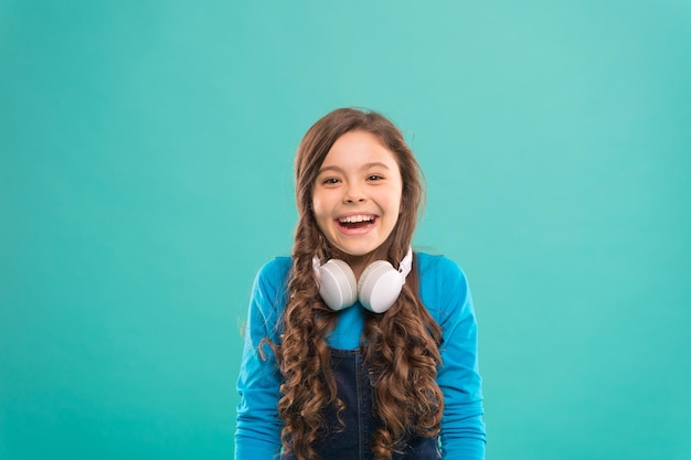 Mergulhe na música DJ pequeno feliz em fundo azul Linda garota sorrindo com fones de ouvido de DJ Criança pequena usando fone de ouvido sem fio para discoteca de DJ Garoto adorável curtindo a música de DJ tocando no rádio