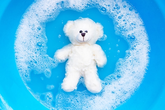 Mergulhe o urso de brinquedo na dissolução da água do detergente antes de lavar. Lavar Roupa,