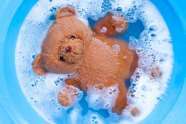 Mergulhe o urso de brinquedo na dissolução da água do detergente antes