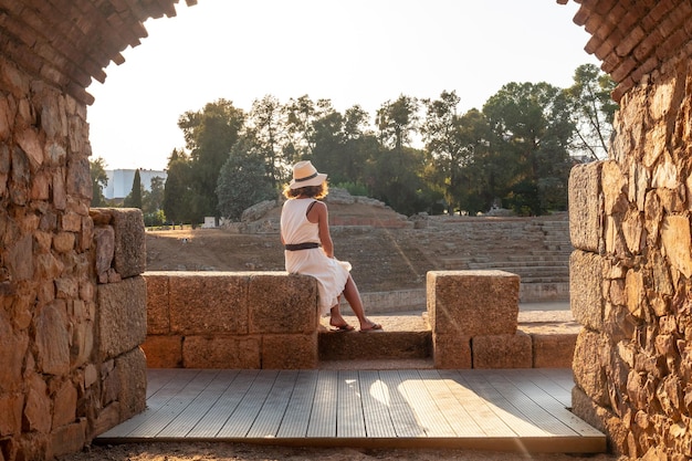 Merida roman ruins eine junge frau, die sitzt und das römische amphitheater estremadura betrachtet