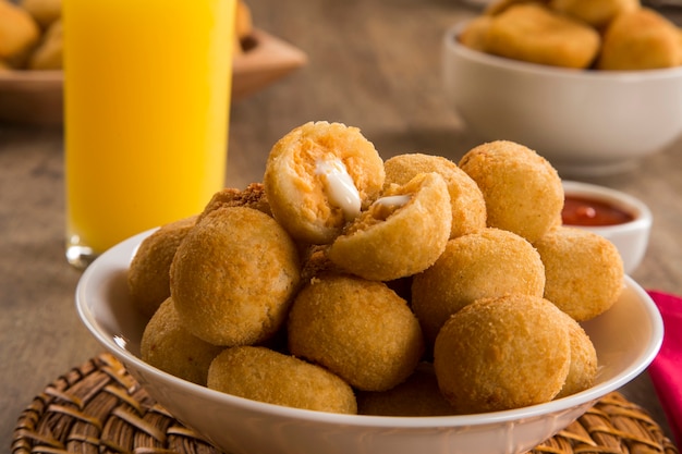 Merienda brasileña. Bola de masa de pollo con cuajada sobre fondo de madera.