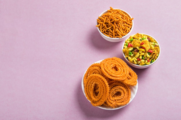 Foto merienda india: chakli, chakali o murukku y besan (harina de gram) sev y chivada o chiwada sobre fondo rosa. diwali food