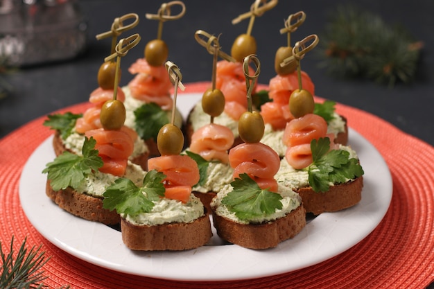 Merienda en una mesa festiva - canapés con salmón, queso crema, aceitunas y aguacate