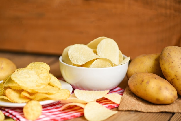 Merienda de papas fritas en un tazón blanco Papas fritas crujientes en la mesa comida y papas crudas frescas sobre fondo de madera