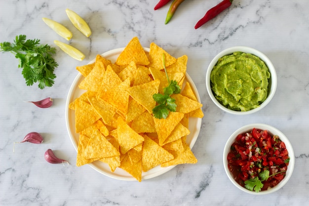 Una merienda tradicional mexicana con nachos servidos con salsas de guacamole, pico de gallo o salsa.