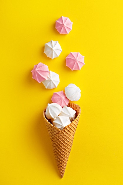 Meringues en cono de helado de waffle sobre un fondo amarillo