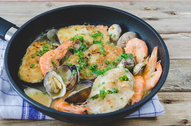 Merluza con gambas y almejas en sartén.