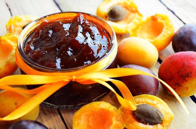 Mermelada de albaricoque y ciruela y fruta fresca en la mesa de madera