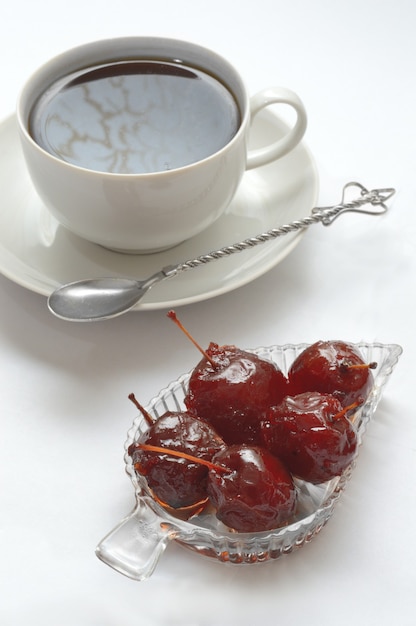 Mermelada en un bol, una taza en un platillo y una cuchara.