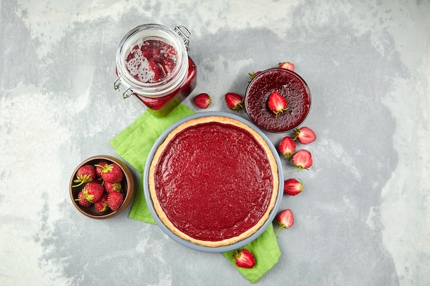 Mermelada casera, mermelada, confitura y tarta con fresas frescas en mesa de hormigón gris