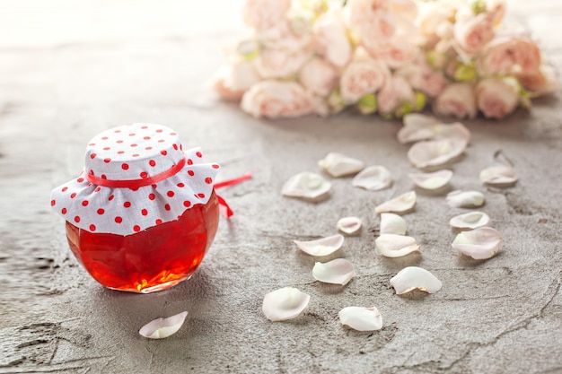 Mermelada casera de pétalos de rosa en la mesa con ramo de rosas.