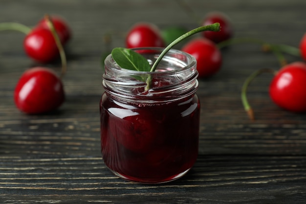 Mermelada de cerezas e ingredientes en la mesa de madera rústica