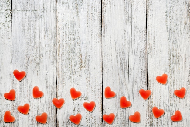 Mermelada dulce caramelo rojo en forma de corazón sobre mesa de madera blanca