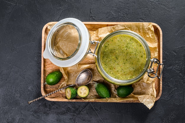 Mermelada de feijoa verde en una tabla de cortar de madera en un frasco de vidrio.