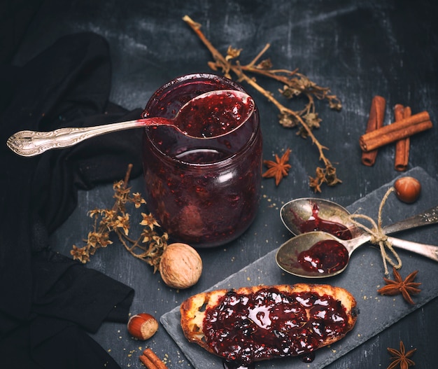 Mermelada de frambuesa en un frasco de vidrio con una cuchara de hierro