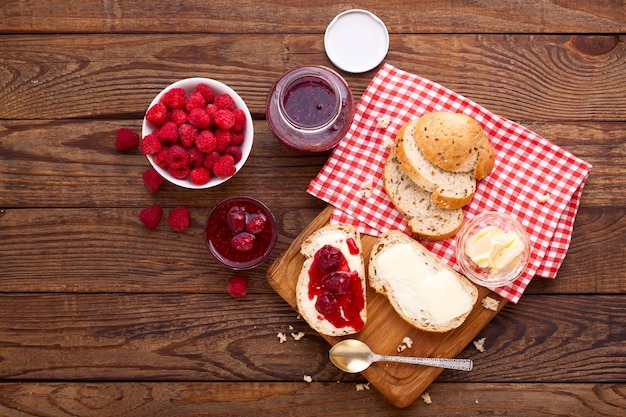 Foto mermelada de frambuesa, pan y mantequilla con frutos rojos en un mostrador de madera