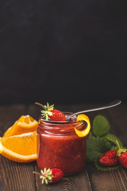 Mermelada de fresa casera o mermelada con naranja en el frasco de vidrio y fresas maduras en la mesa de madera Cerrar departamento poco profundo del espacio de copia de campo