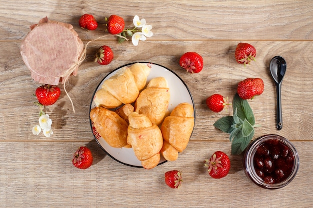 Mermelada de fresa casera tradicional en frascos y plato con croissants, decorado con fresas frescas Vista superior