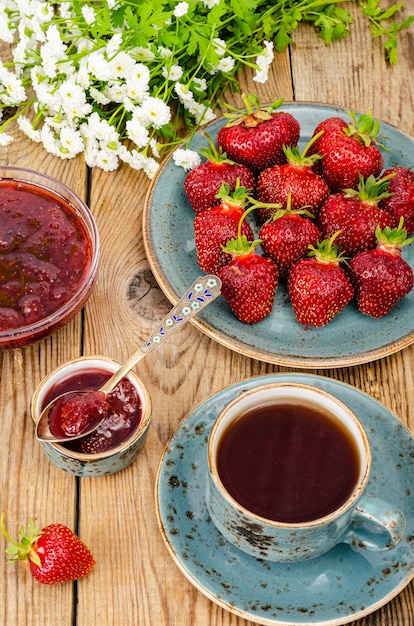 Mermelada de fresa dulce roja madura, bayas frescas en mesa de madera