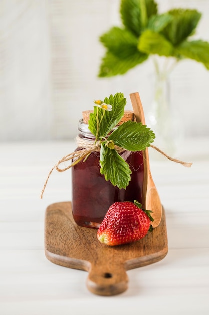 Mermelada de fresa en un frasco sobre una tabla de madera bayas fermentadas