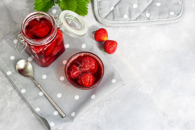 Mermelada de fresa en un frasco de vidrio junto a fresas frescas