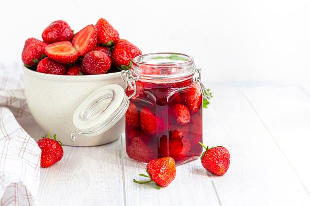 Mermelada de fresa en un frasco de vidrio junto a fresas frescas