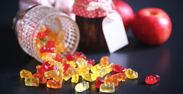 Mermelada en un jarrón sobre la mesa Dulces en un bol sobre un fondo negro Dulces de gelatina multicolor para niños