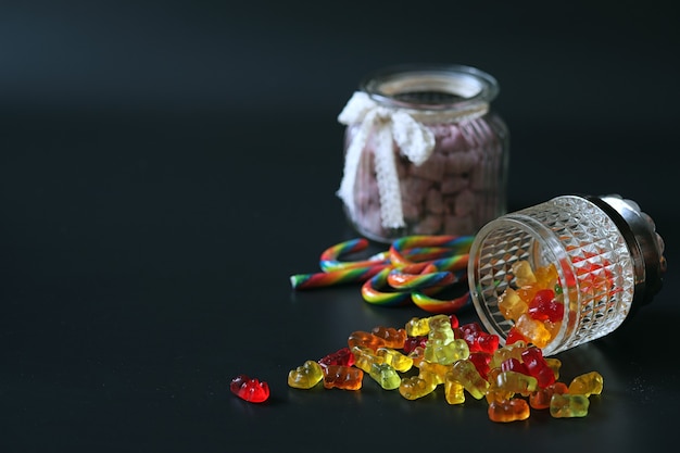 Foto mermelada en un jarrón sobre la mesa. dulces en un cuenco sobre un fondo negro. caramelos de gelatina multicolor para niños.