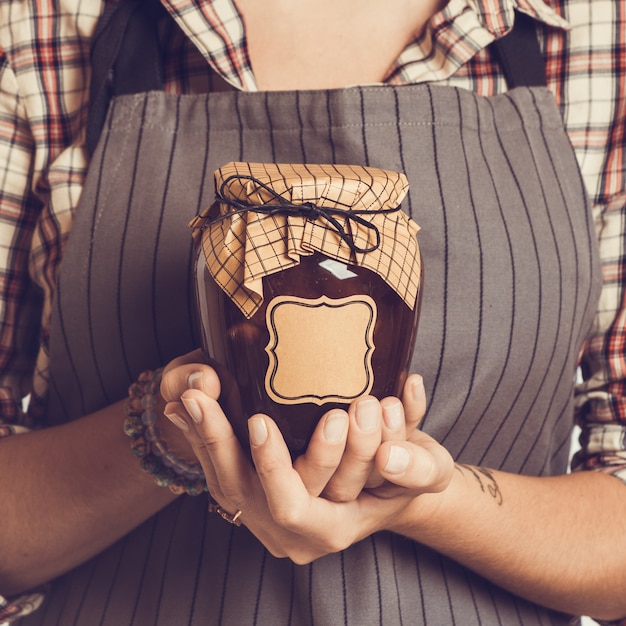 Mermelada de melocotón de banco vintage en manos de mujeres. De cerca